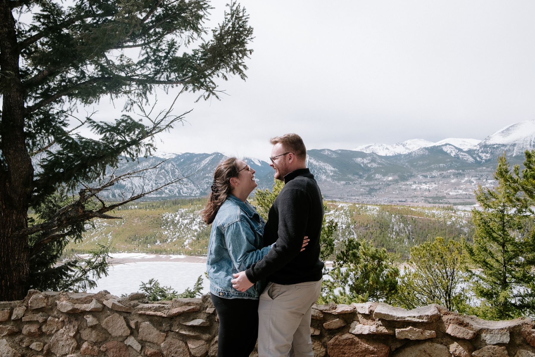 Newly engaged couple embracing at a mountain overlook with stunning views